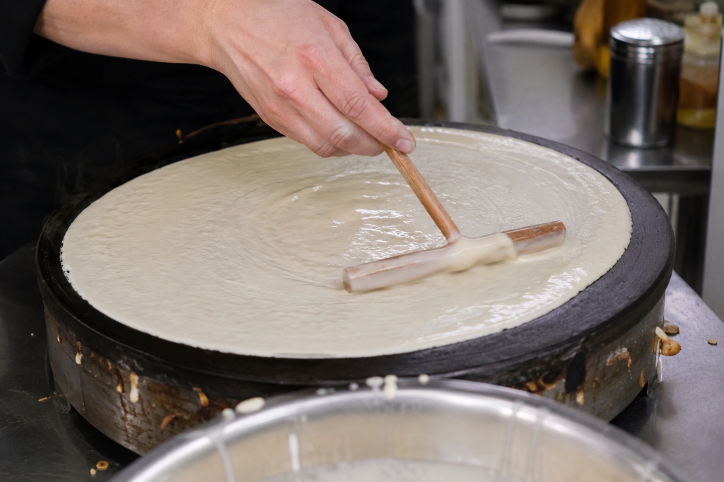Fotografia real da massa de crepe sendo espalhada